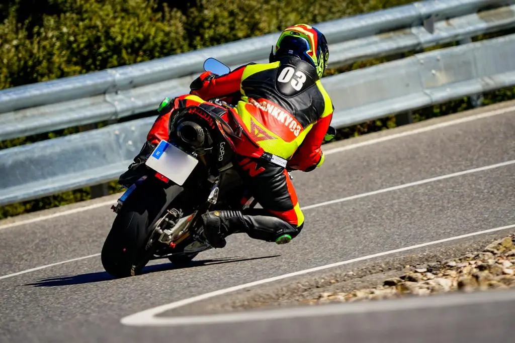 Motociclist cu echipament personalizat roșu și negru pe circuit