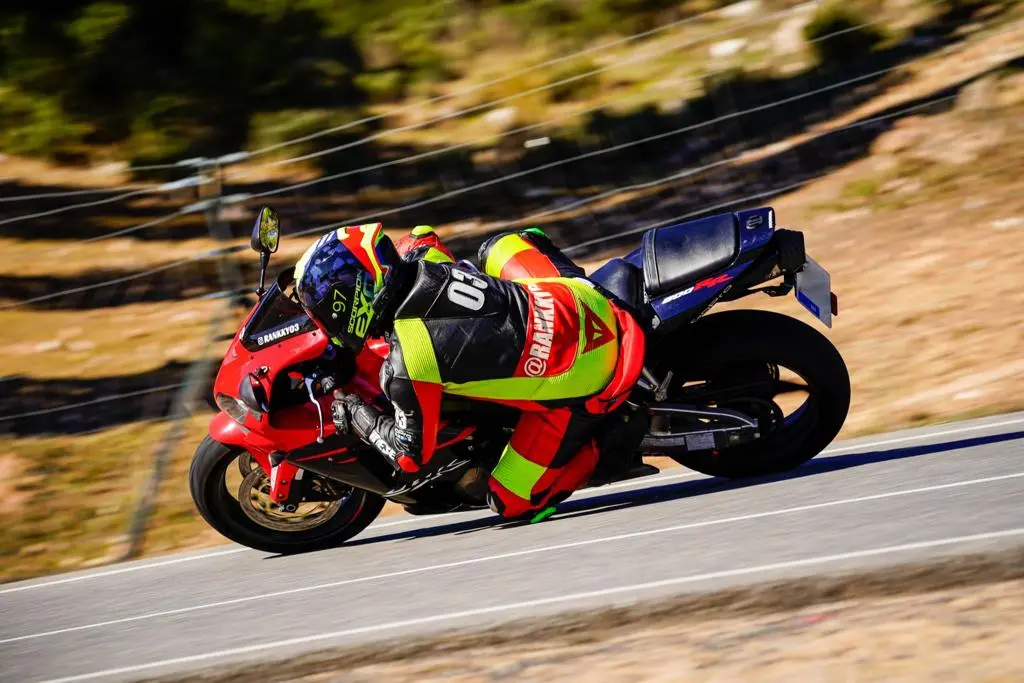 Pilot aplecat în viraj cu motocicletă sport roșie