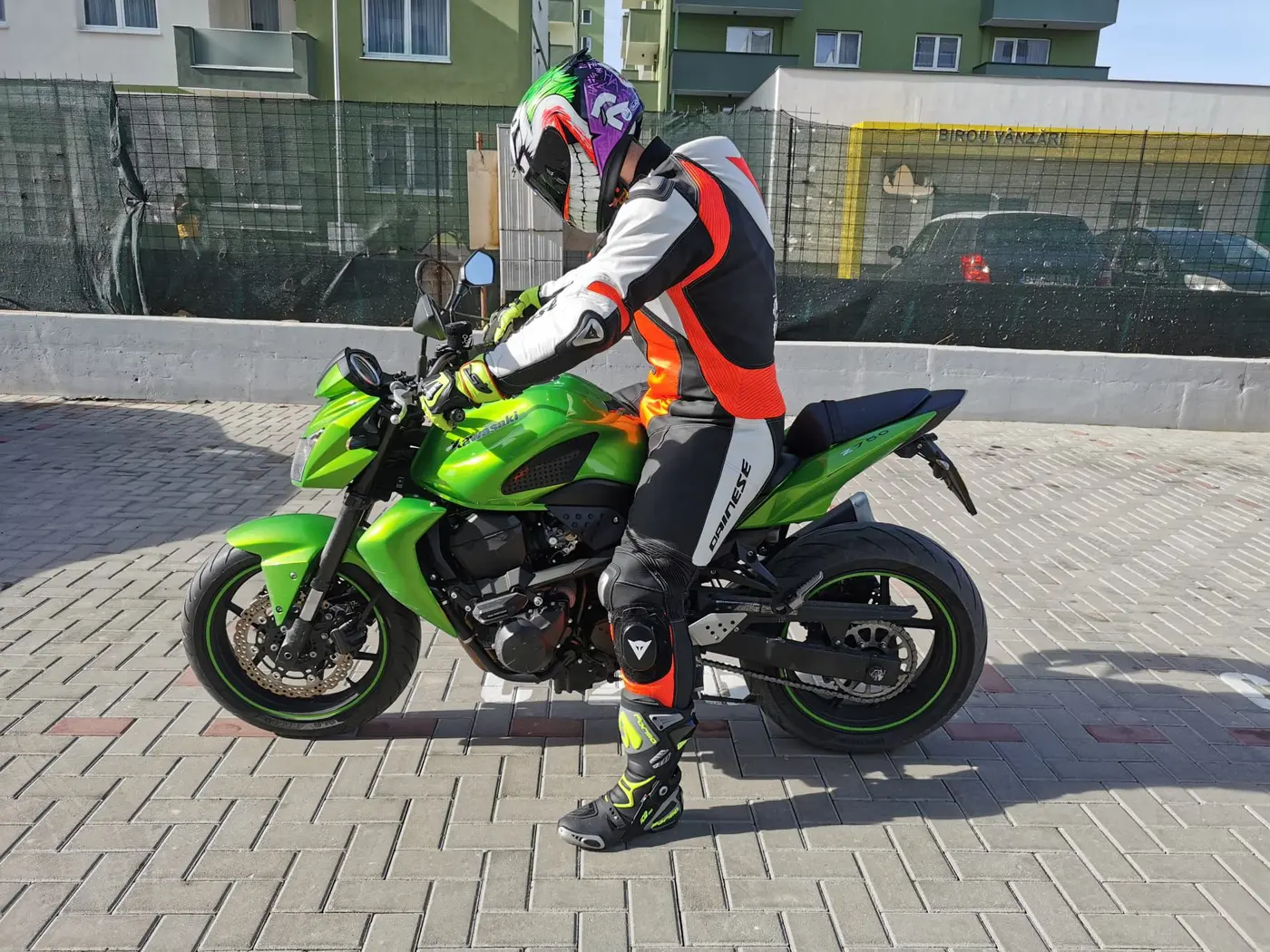 Client în echipament alb, negru și roșu pe motocicletă verde